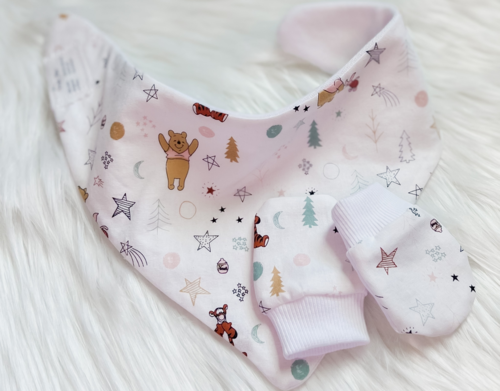 Baby bib and mittens with bear and star patterns on a white background