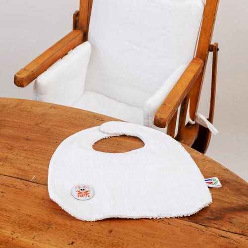 White baby bib on a wooden chair with a white cushion