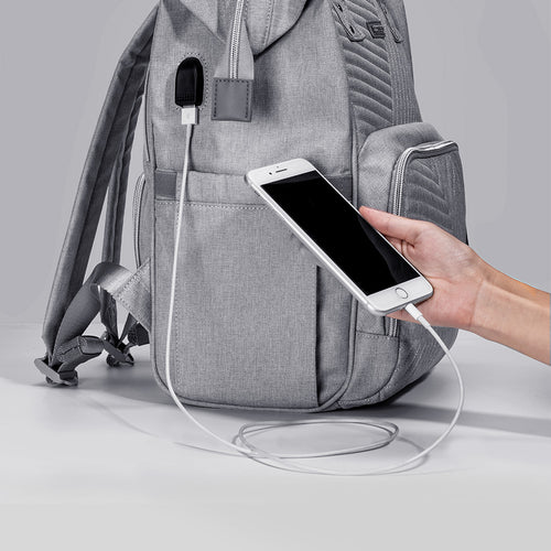 Gray backpack with a USB port being used to charge a smartphone.