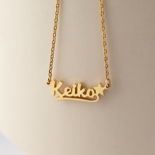 Gold name necklace with 'Keiko' on a beige background