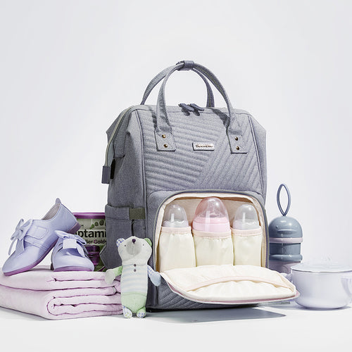 Gray diaper bag with baby items on a white background