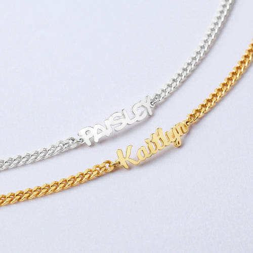 Two name bracelets, one silver and one gold, on a light gray background.